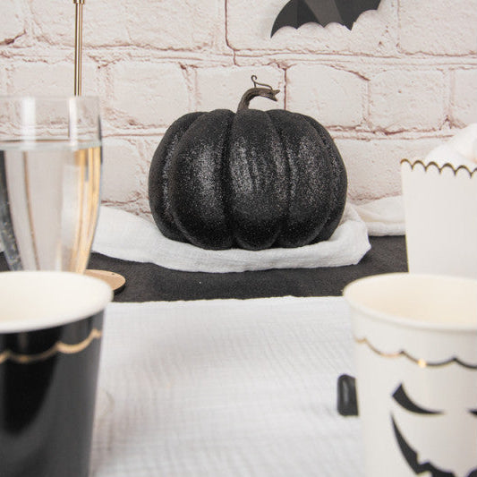 Black and white Halloween-themed table setting with a black glittery pumpkin centerpiece