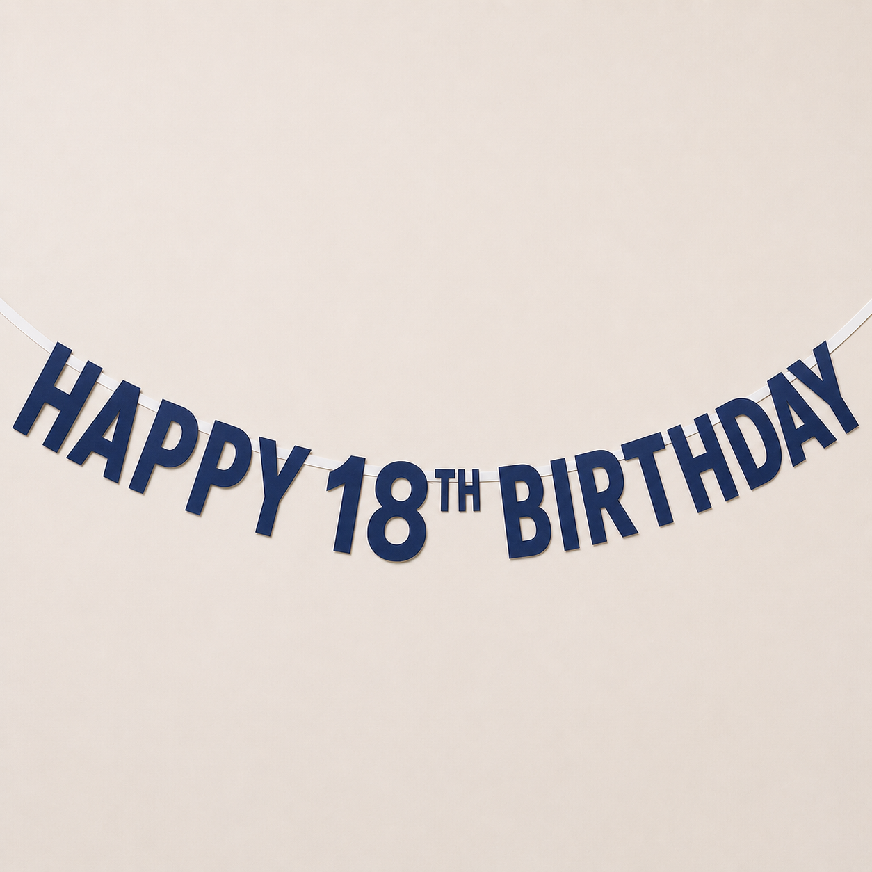 A navy blue 'HAPPY 18TH BIRTHDAY' paper banner garland strung against a plain beige wall.