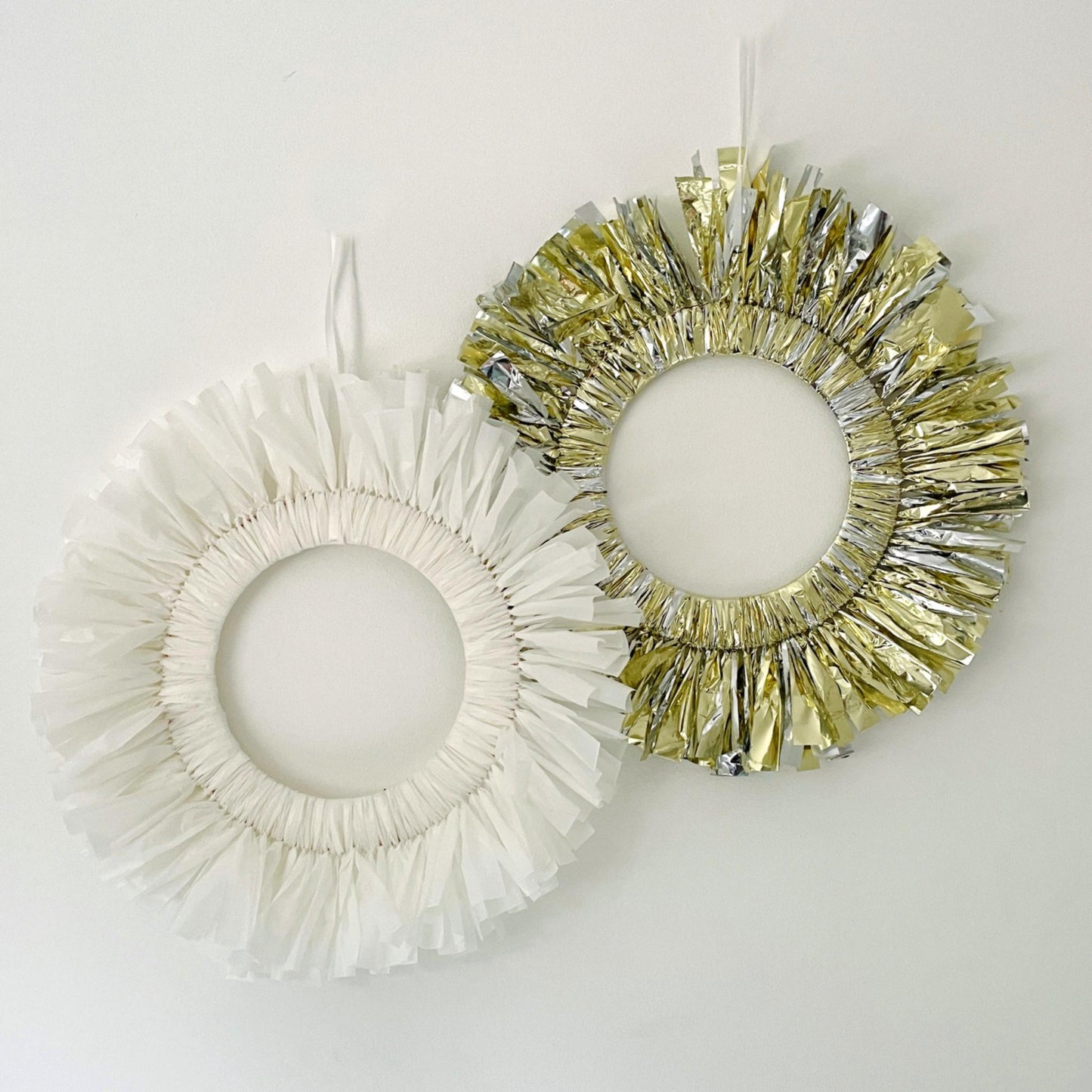 Two decorative wreaths, one white and one gold, on a light gray background.