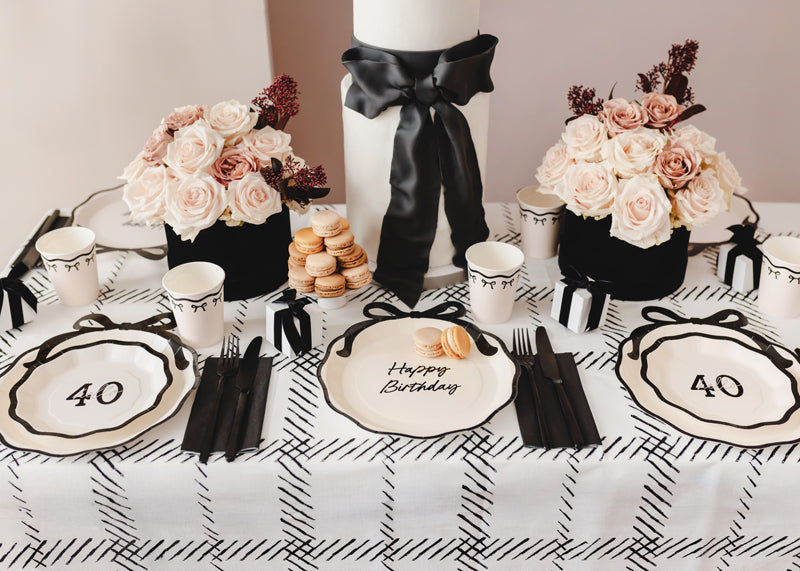 Table setting with 'Happy Birthday' and number '40' decorations, flowers, and candles.