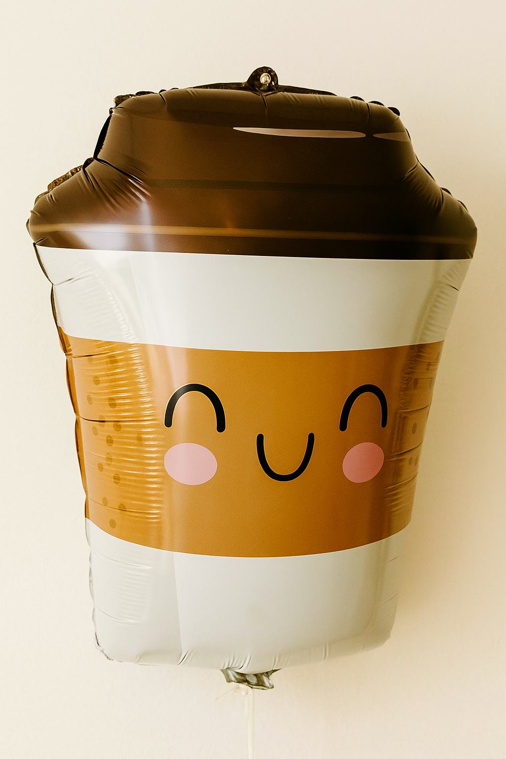 Balloon shaped like a coffee cup with a face on a beige background