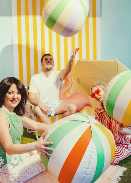 Two adults and a child playing with colorful beach ball balloons