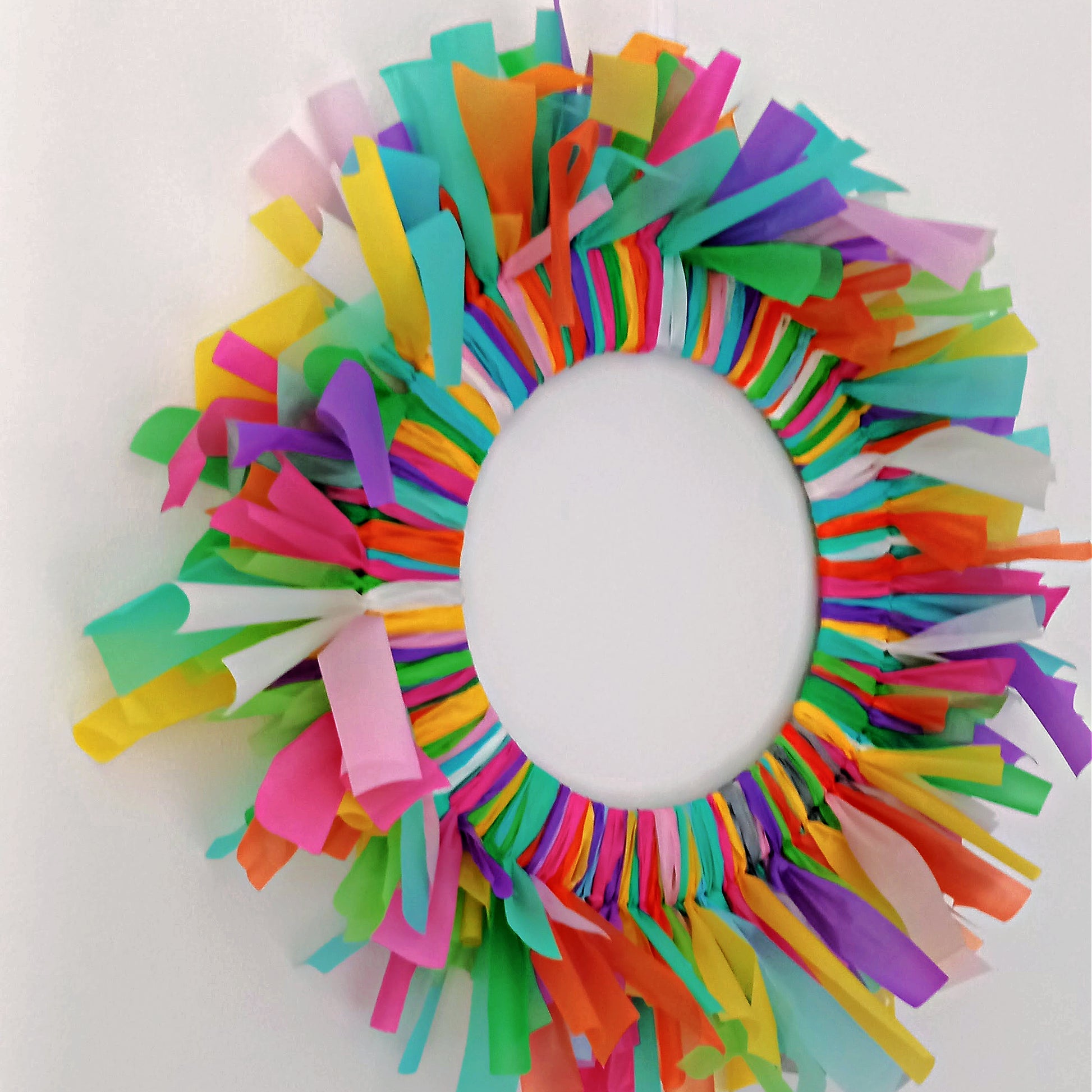 Close-up of bright streamer off-cuts on eco-friendly reusable birthday wreath, handmade in London.