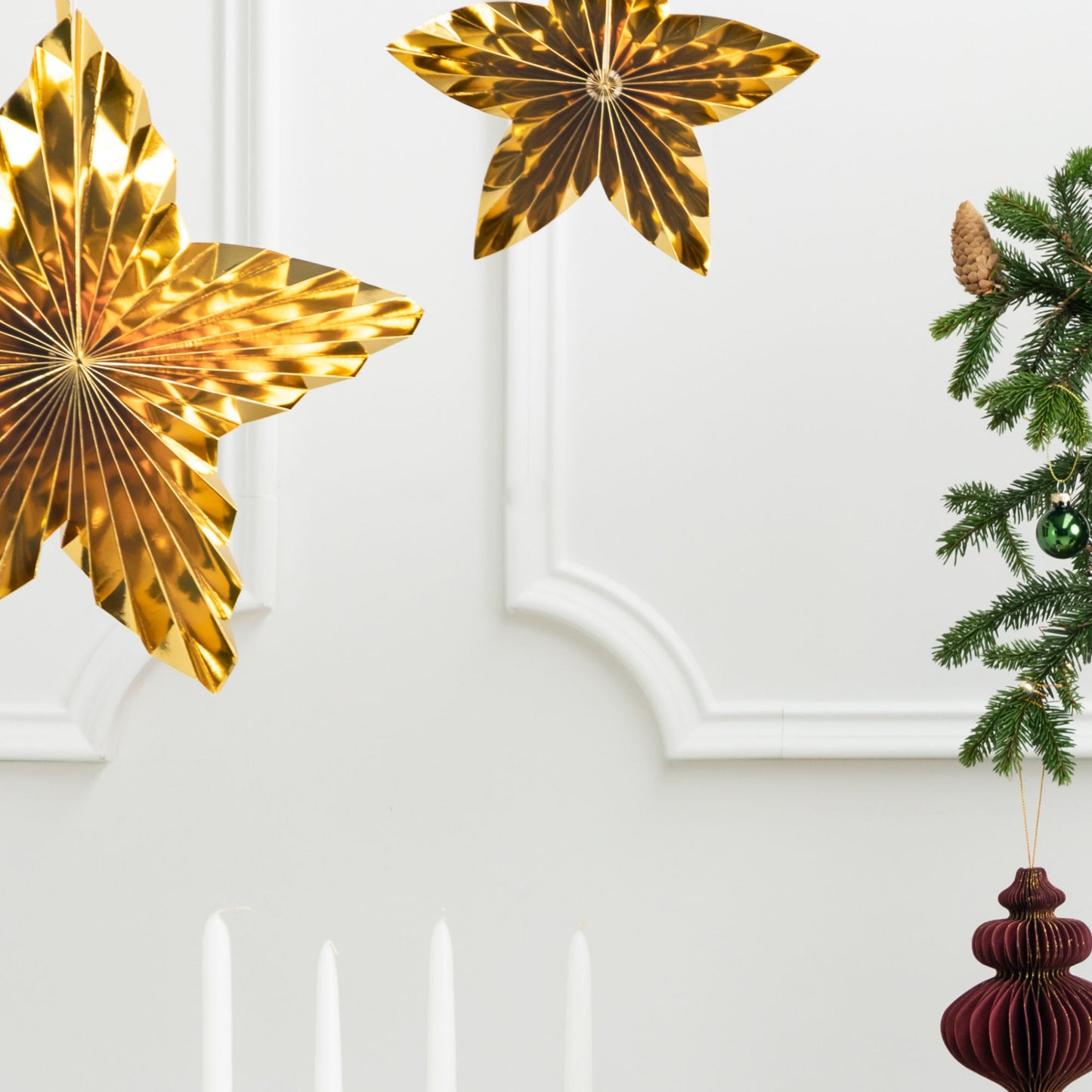 Set of 3 metallic gold hanging paper star decorations in three sizes.