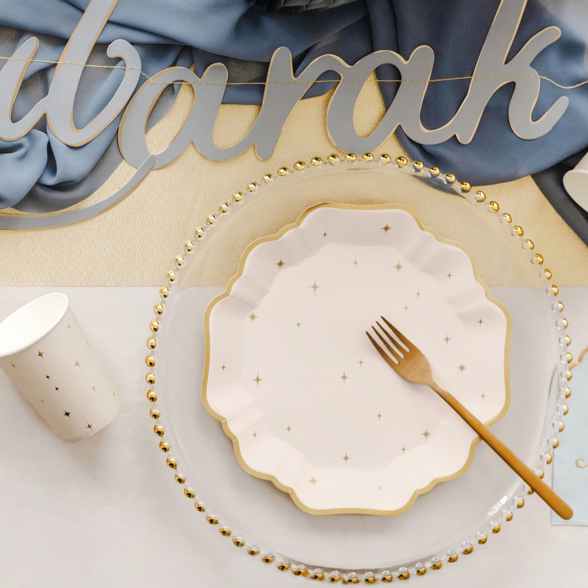 Cream scalloped paper party plates with metallic gold stars and gold edging.