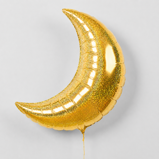A crescent moon-shaped metallic gold foil balloon with a glittery texture, shown against a light gray background.