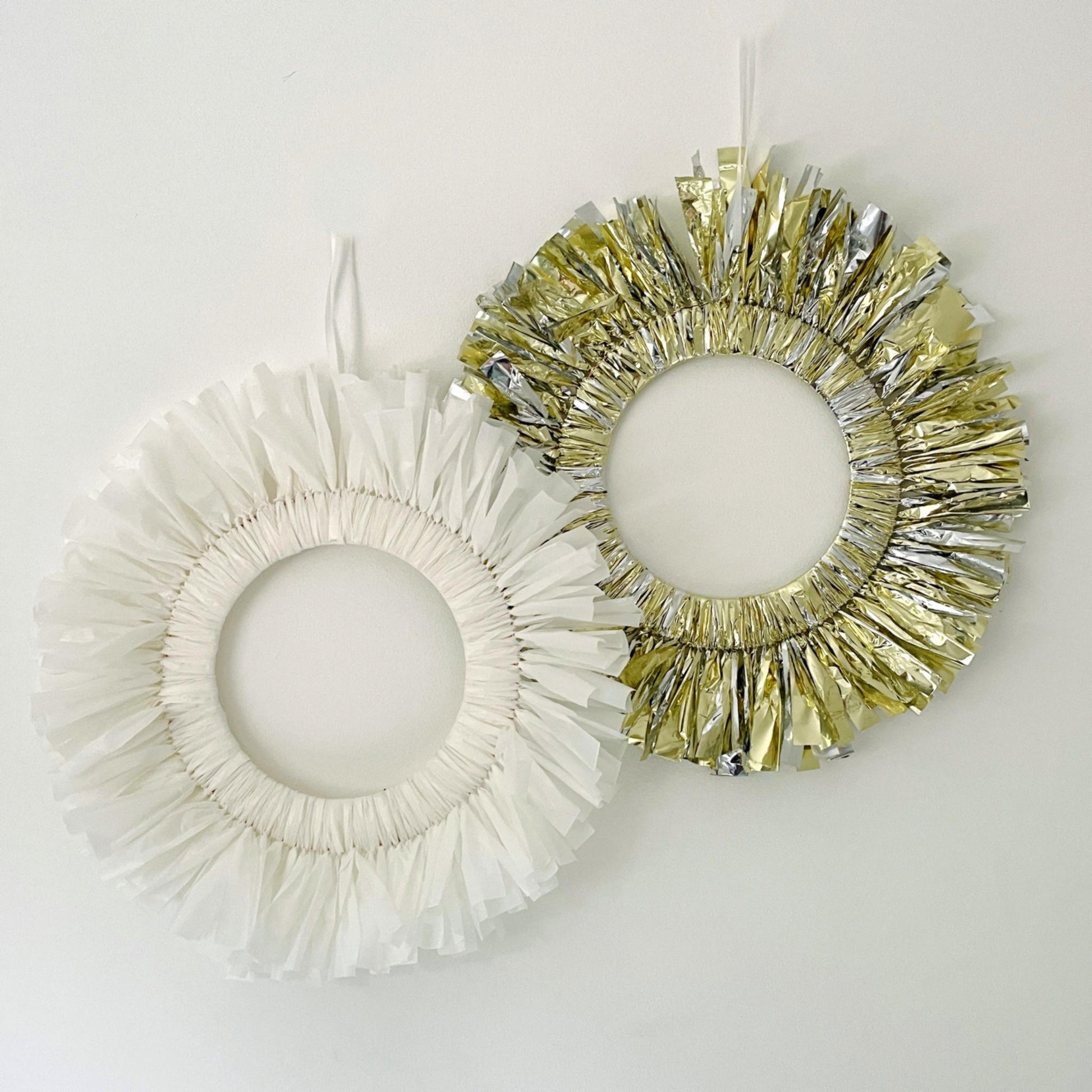 Two decorative wreaths, one white and one gold, on a light gray background.
