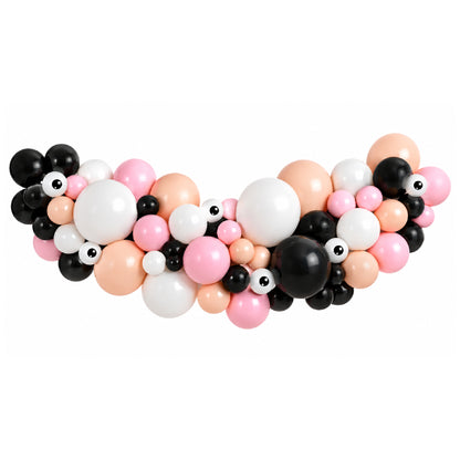 A halloween themed balloon garland decoration featuring a mix of black, white, pink, and peach balloons, including several novelty googly eyes, arranged in a curved shape against a solid white background.