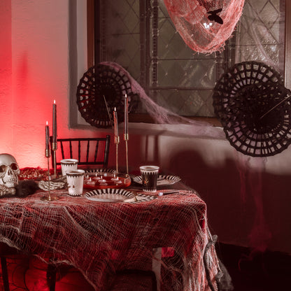 Halloween-themed table setting with candles, skull, and spider web decorations.