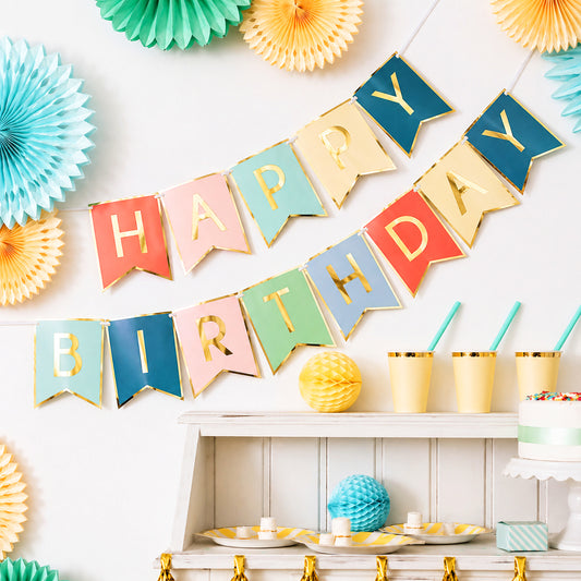 Colorful 'Happy Birthday' banner with party decorations on a white wall.