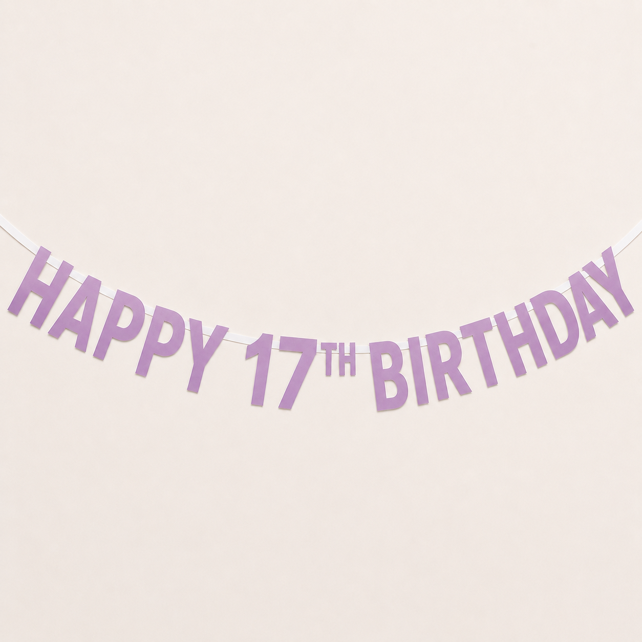 A lavender 'HAPPY 17TH BIRTHDAY' banner garland strung against a plain cream-colored background.