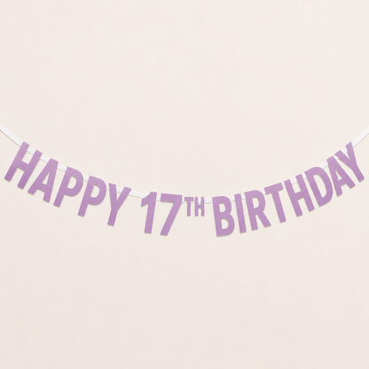 A lavender 'HAPPY 17TH BIRTHDAY' banner garland strung against a plain cream-colored background.