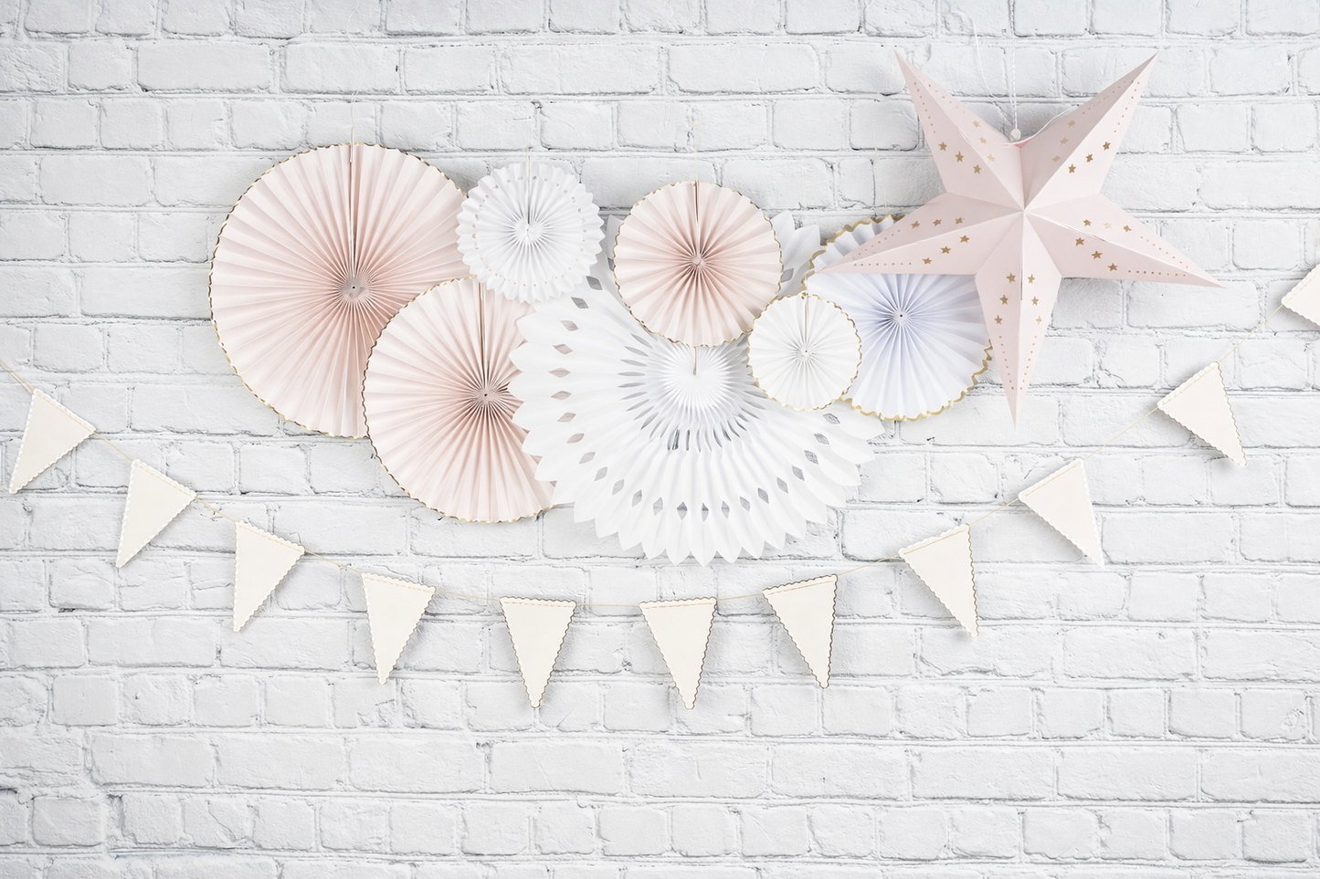 Decorative paper fans and stars on a white brick wall