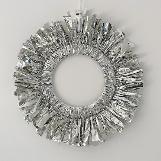 Decorative silver wreath hanging on a white wall