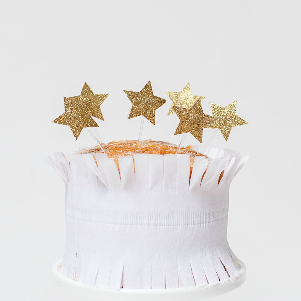 gold glitter star toppers on top of a cake.