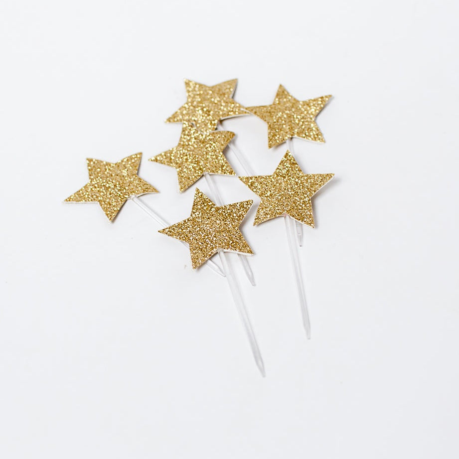 gold glitter star toppers on top of a cake.