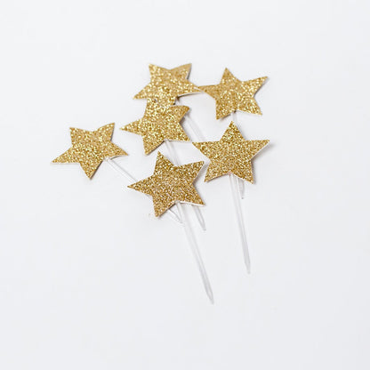 gold glitter star toppers on top of a cake.